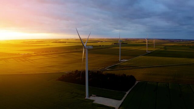 Solar power plant and Windmills aerial view. Renewable energy. Green tech. Windmill Turbines Clean, Green Wind Energy. Large wind turbines with blades in field, orange sunset, epic heavy clouds. 