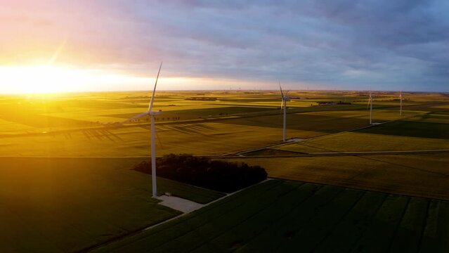 Solar power plant and Windmills aerial view. Renewable energy. Green tech. Windmill Turbines Clean, Green Wind Energy. Large wind turbines with blades in field, orange sunset, epic heavy clouds. 