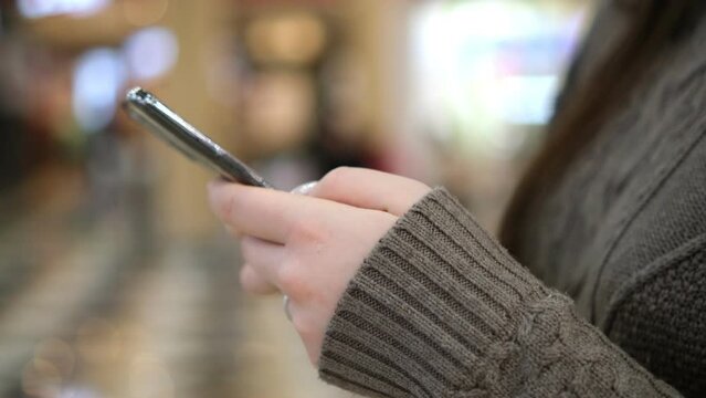 Shopping center. Moll. Finger of woman touching scroll page app on mobile phone. Browsing movie video in the internet library to watch film online.