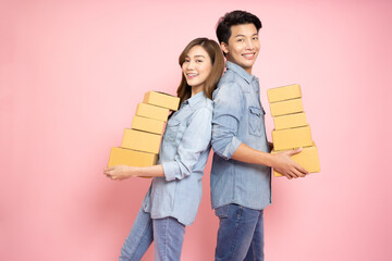 Asian couple holding package parcel box isolated on pink background, Delivery courier and shipping...