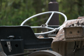 The steering wheel of an old tractor seen from close up. Side view with steering wheel, control...