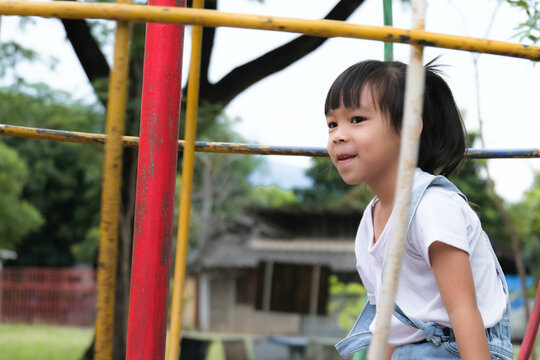 Cute little girl having fun in the outdoor playground. Young girl playing swings in the garden. Healthy summer activity for children.