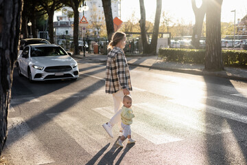 Father and toddler girl walking on crosswalk on urban street in Treviso.