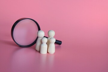 Wooden dolls and magnifying glass. Finding a partner to create a family, adoption of kid concept.