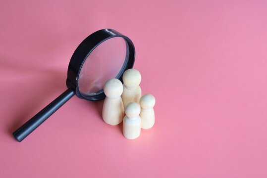 Wooden dolls and magnifying glass. Finding a partner to create a family, adoption of kid concept.