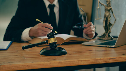 Legal Counsel Concept Lawyer working on office documents with legal tiger skins and injustice goddess scales hammer on the table.