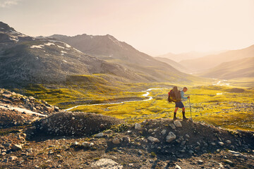 Obraz premium Hiker tourist walking at mountain valley at sunset
