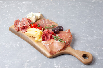 Charcuterie and cheese board with a place for text. Prosciutto di Parma ham, blue cheese. Italian appetizers or antipasto set with gourmet food on table, top view.