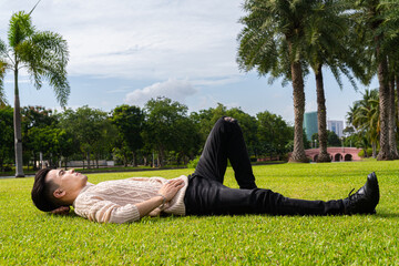 Handsome young man laying down on grass during summer at park - 507122818