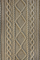 Beige background knitted fabric with a pattern. Knitted Arans close-up