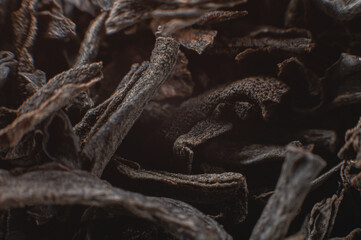 Black loose leaf tea as a background. Texture of dry black tea leaves. Dark background. Extreme macro mode. black leaf tea closeup