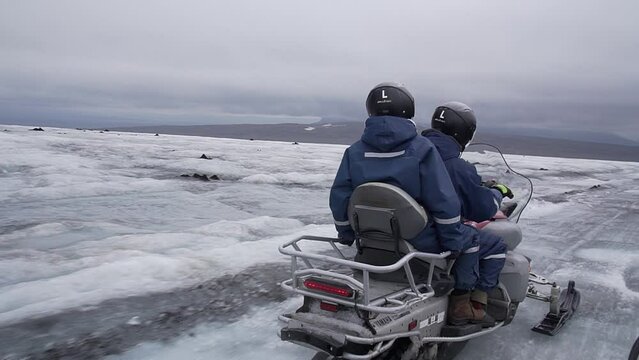 Aroup of tourists riding snowmobiles with a guide at Vatnajokull glacier in Iceland. Active sport, recreation, lifestyle.