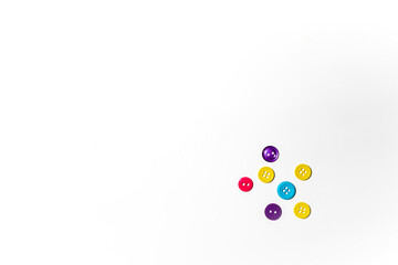 Plastic buttons in different colors laying on white background with copy space