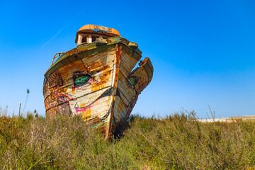 wreck of a fishing boat on land covered with grass
