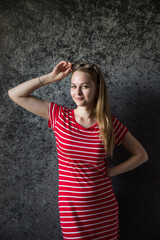 The girl the blonde in a red striped dress with glasses on a dark background.