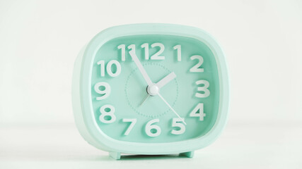 Blue table clock with arrows on a white table