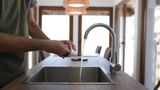 Man washing coffee cup at kitchen sink
