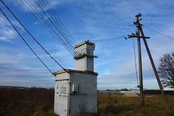 An old electrical transformer booth and electrical poles in the countryside .
