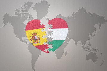 puzzle heart with the national flag of hungary and spain on a world map background. Concept.