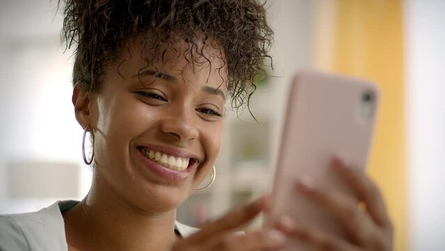 
Close up of Happy African American Young Woman Using Smartphone Working or Studying From Home. Video Conference Call at Home Office. Friends Chatting, Online Learning or Teleworking Concept.
