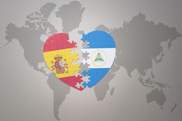 puzzle heart with the national flag of nicaragua and spain on a world map background. Concept.
