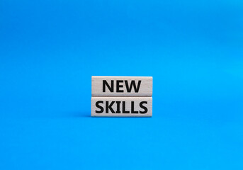 New skills symbol. Concept words 'new skills' on wooden blocks. Beautiful blue background. Business and new skills concept. Copy space.
