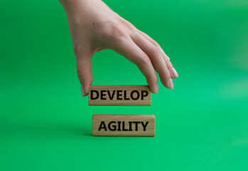 Develop agility symbol. Concept word Develop agility on wooden blocks. Beautiful green background. Businessman hand. Business and Develop agility concept. Copy space