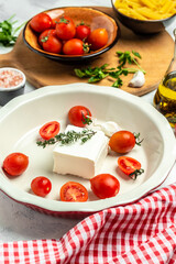 cooking recipe Fetapasta with cherry tomatoes, feta cheese, garlic and thyme on white plate. top view