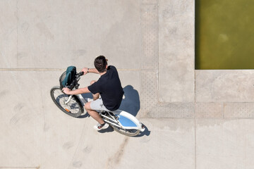 Young man riding his bike and exercising in Stavros Niarchos Cultural Center in Athens, Greece, aerial view with minimal framing and negative space on concrete background