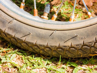 Dirty motorcycle wheel and tire detail, on the grass.