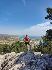 Blonde sport woman in sportwear running on mountain path. Summer vacations in Greece, Rhode Island