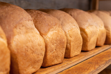 Close-up of freshly baked bread on wooden shelves. Production of bakery products