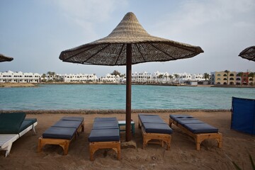 An umbrella and sunbeds, on a beach in Hurghada, Egypt, on a cloudy day.