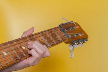 Pinch a chord on the guitar neck with your fingers on a yellow background
