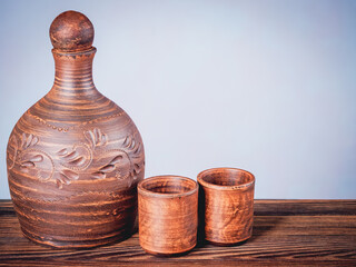 Clay jug and two cups on a wooden board in still life style