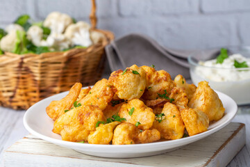 Fried in batter Cauliflower florets served on a black plate on a grey concrete table with ingredients, view from above, close-up, flatlay, copy space