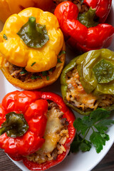 Stuffed peppers, halves of peppers stuffed with rice, dried tomatoes, herbs and cheese in a baking dish on a blue wooden table, top view. (Turkish name; biber dolmasi)