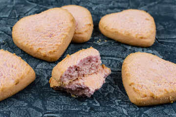 Broken heart-shaped cookies on a black (dark) background. The texture of the cookie inside.