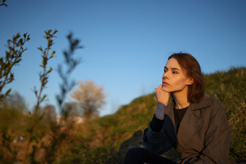 Gorgeous brunette girl sits on a green field. 