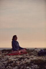 Woman practicing yoga outdoors in sunset sunrise time.