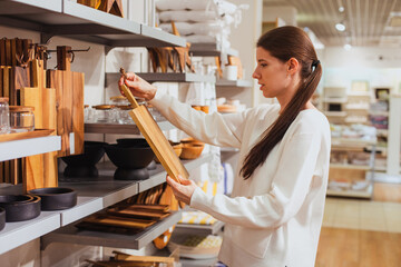 Young happy smiling millennial woman with long dark hair in pony tail is choosing home decor,...