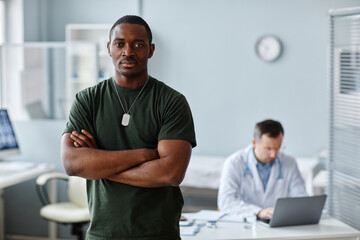 Fototapeta premium Portrait of strong young Black soldier standing with arms crossed posing on camera during medical checkup