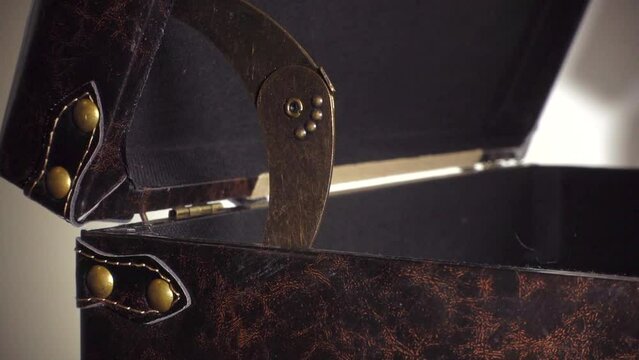 Closeup of a hinged lid of a sturdy brown leather storage case slowly opening, a colorful scarf being added, then the lid being closed.
