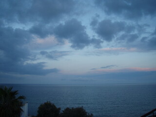 Atardecer en la mar con fondo de azul marino y horizonte y frente nuboso bajo, además de nubes...