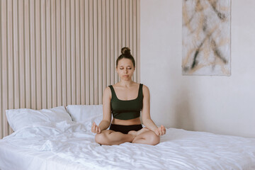 A young caucasian mindful woman meditates holding fingers in yoga sign with her eyes closed sitting...