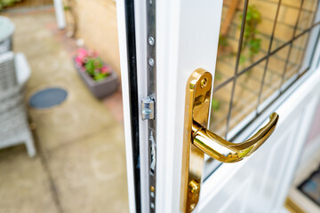 Shallow focus of the brass coloured door handle on a newly installed double glazed door. Showing...