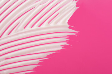 Abstract smear of white cosmetic cream on the pink background,abstract form.