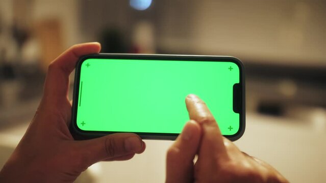 Close up shot of person playing video games on smartphone with chroma key green screen. Technology concept.
