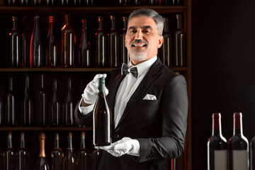 Elegant waiter sommelier wine steward with a bottle of wine. Examination of wine products....
