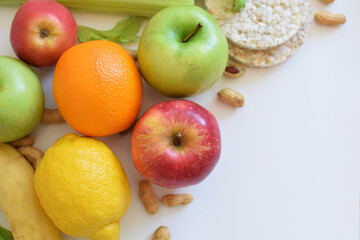 Healthy food. Fresh fruits. Green and red apples, banana, celery, pear, grain bread, nuts, orange, lemon, greens. Concept of good meals.